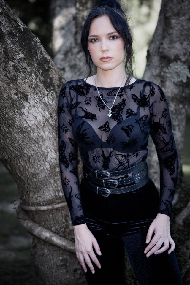 Sheer black mesh long sleeve top featuring Ami Raithe moth artwork with hand-drawn insects scattered across delicate transparent fabric. This whimsigoth layering top blends dark fairycore, gothic fashion and fantasy witch aesthetics with a flattering boat neckline and fitted silhouette.